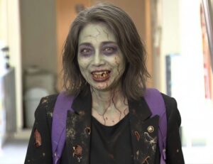 ゾンビのようなメイクと朽ちた服を着て、ぼろぼろの歯で不気味に笑う田久保真紀市長のクローズアップ。